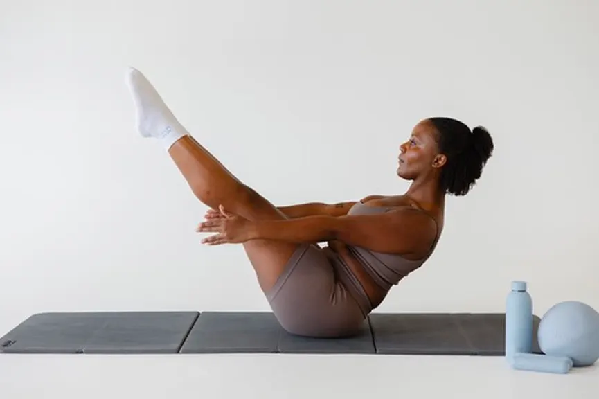 Pilates teaser on a mat with a water bottle and ball nearby